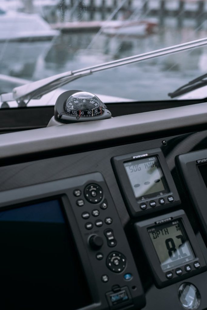 Detailed view of a boats control panel featuring a compass and GPS navigation displays in a marina.