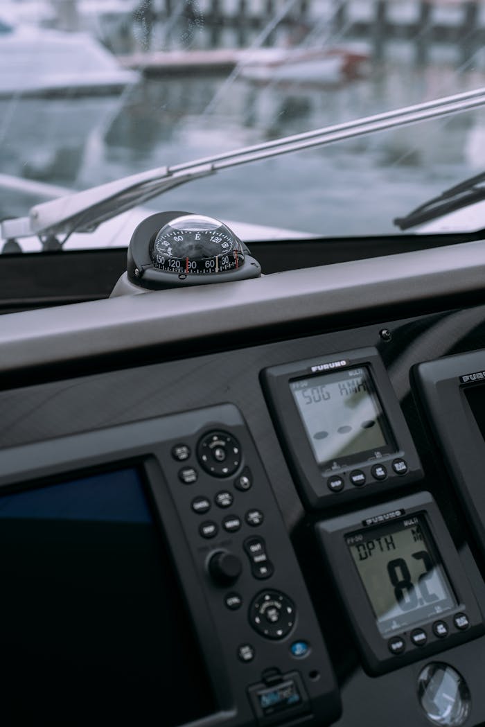 Detailed view of a boats control panel featuring a compass and GPS navigation displays in a marina.